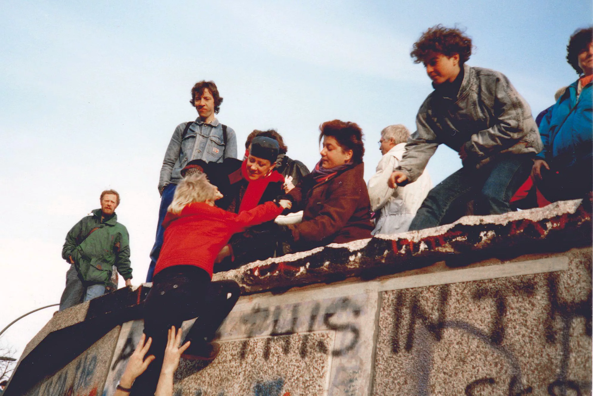 Giovani scavalcano il muro di Berlino